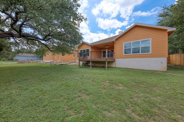 back of property with a yard, ceiling fan, and a wooden deck