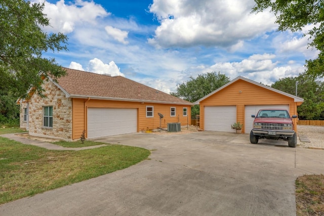 single story home featuring a front lawn, a garage, an outbuilding, and central AC