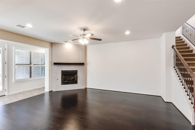 unfurnished living room with ceiling fan, a large fireplace, and dark hardwood / wood-style floors