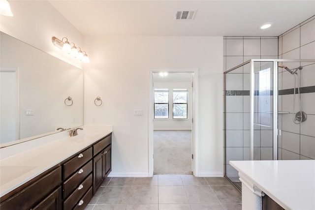 bathroom featuring tile patterned flooring, a shower with shower door, and vanity