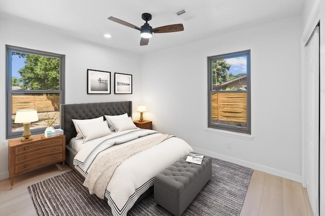 bedroom with ceiling fan, light hardwood / wood-style floors, and multiple windows