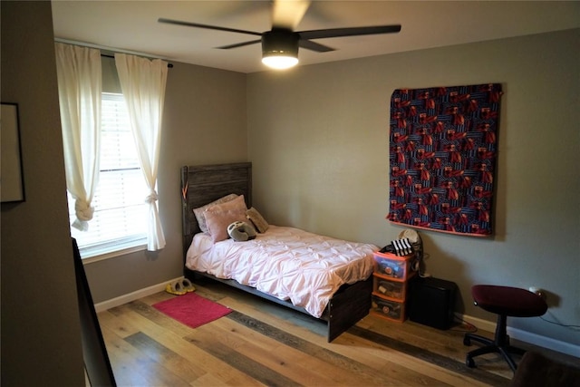 bedroom featuring hardwood / wood-style floors, ceiling fan, and multiple windows