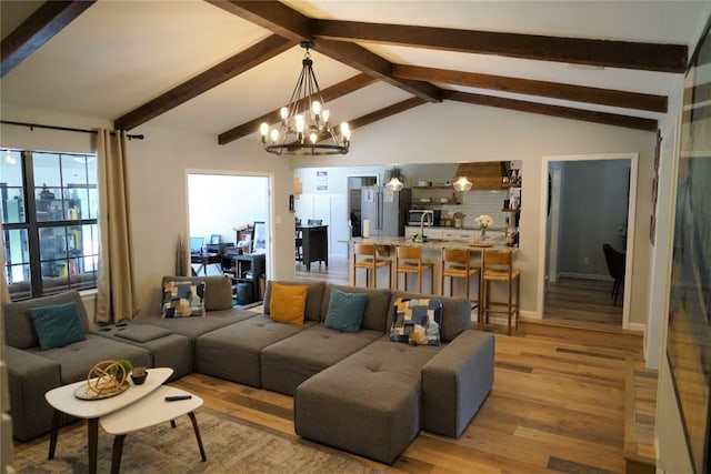 living room featuring vaulted ceiling with beams, a notable chandelier, and light wood-type flooring