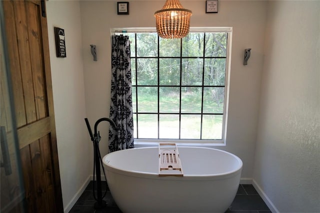 bathroom featuring a washtub, a chandelier, tile patterned floors, and plenty of natural light