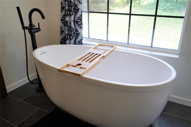 bathroom with a bathing tub, tile patterned floors, and a wealth of natural light