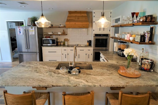 kitchen with decorative backsplash, appliances with stainless steel finishes, a kitchen breakfast bar, custom range hood, and white cabinetry