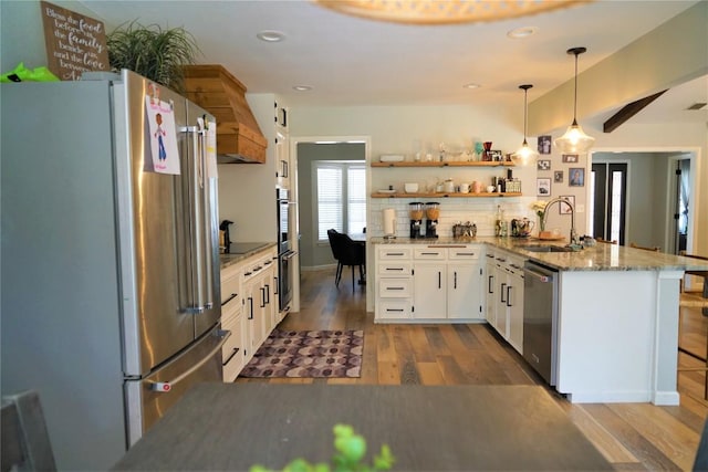 kitchen with dark hardwood / wood-style floors, kitchen peninsula, decorative light fixtures, white cabinets, and appliances with stainless steel finishes