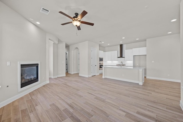 unfurnished living room featuring light hardwood / wood-style flooring, ceiling fan, and sink