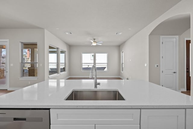 kitchen with dishwashing machine, an island with sink, light stone counters, and sink