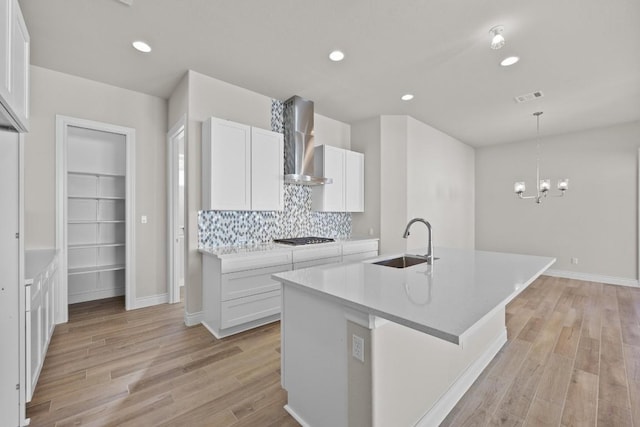 kitchen featuring white cabinetry, sink, wall chimney exhaust hood, and light hardwood / wood-style flooring