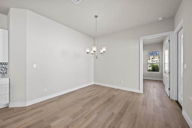 unfurnished dining area featuring light hardwood / wood-style floors and a chandelier