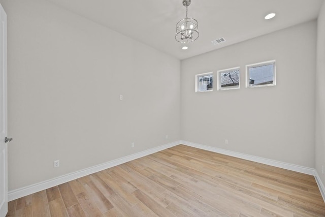 spare room featuring light hardwood / wood-style floors and a notable chandelier