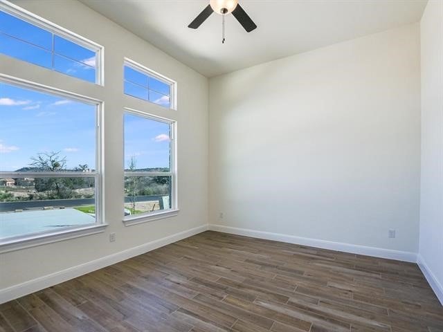 empty room with ceiling fan and dark wood-type flooring