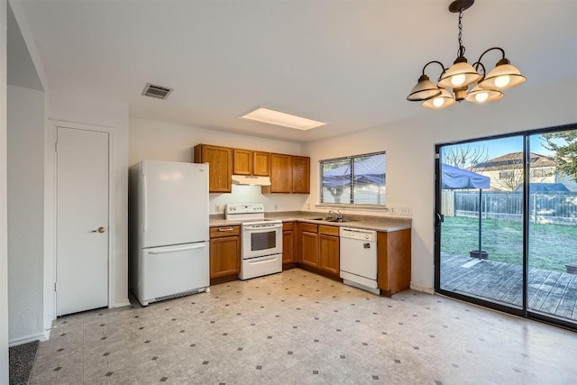 kitchen with white appliances, hanging light fixtures, a notable chandelier, and sink