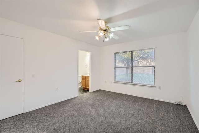 unfurnished bedroom featuring ensuite bathroom, dark carpet, and ceiling fan