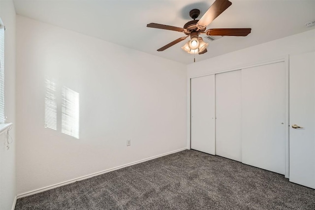 unfurnished bedroom with dark colored carpet, ceiling fan, and a closet