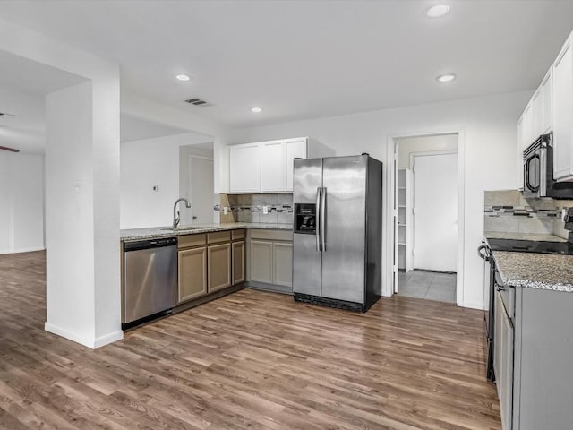 kitchen with white cabinets, sink, tasteful backsplash, light stone counters, and stainless steel appliances