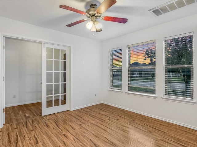 unfurnished room with hardwood / wood-style floors, ceiling fan, and french doors