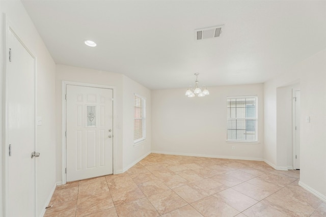 tiled empty room featuring an inviting chandelier