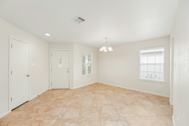 empty room with light tile patterned flooring and an inviting chandelier