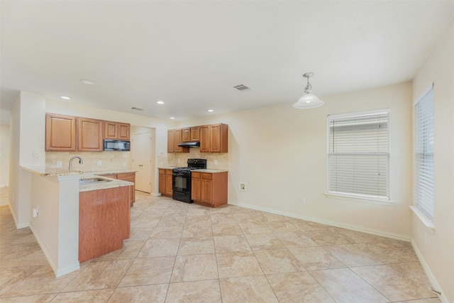 kitchen featuring pendant lighting, black appliances, sink, decorative backsplash, and kitchen peninsula