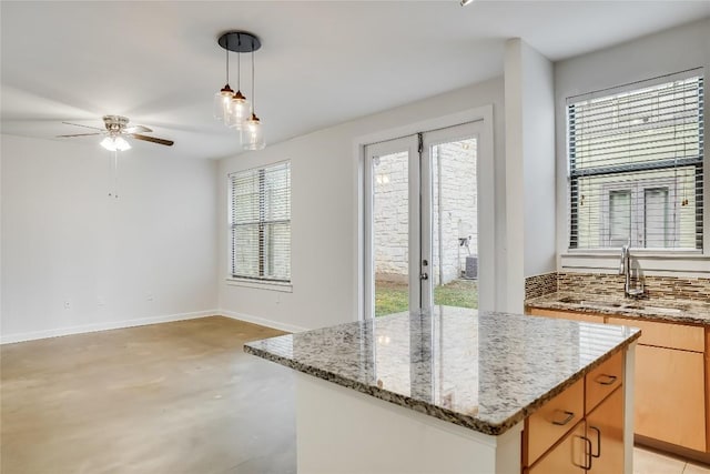 kitchen featuring light stone countertops, sink, a center island, hanging light fixtures, and backsplash