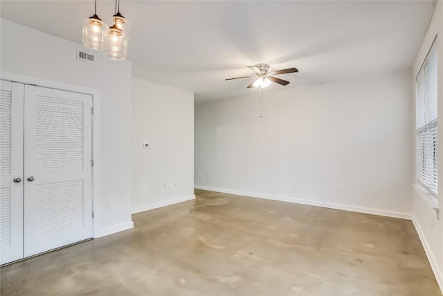 unfurnished room with ceiling fan and concrete flooring