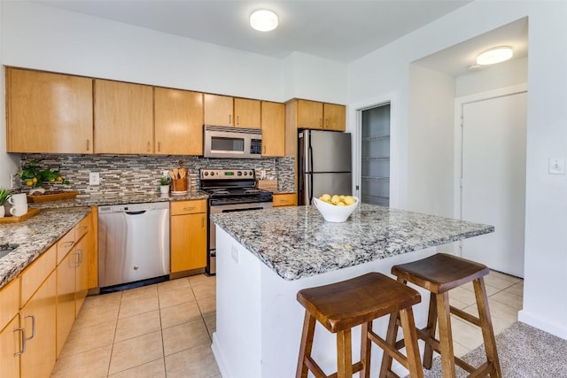 1201 Grove Blvd Unit 1102, Austin, TX 78741 - kitchen with stainless steel appliances, decorative backsplash, a breakfast bar, light tile patterned floors, and light stone countertops