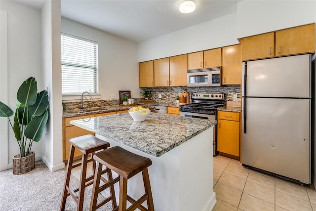 1201 Grove Blvd Unit 1102, Austin, TX 78741 - kitchen featuring appliances with stainless steel finishes, tasteful backsplash, a breakfast bar, a kitchen island, and light stone counters