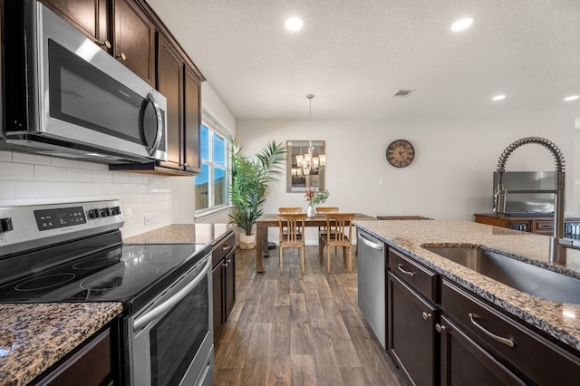 kitchen with appliances with stainless steel finishes, sink, a chandelier, dark hardwood / wood-style floors, and hanging light fixtures