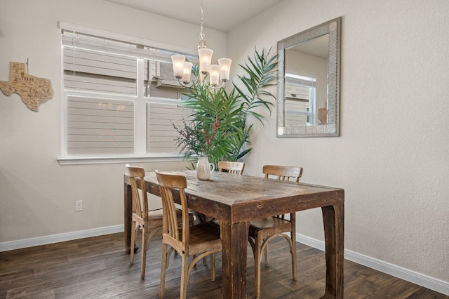 dining area with dark wood-type flooring and an inviting chandelier