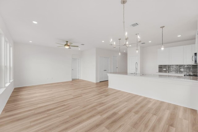 kitchen featuring a sink, light countertops, stainless steel microwave, recessed lighting, and white cabinetry