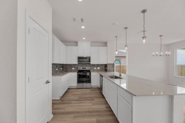 kitchen with visible vents, decorative backsplash, a peninsula, a sink, and stainless steel appliances