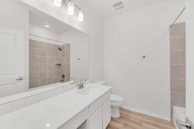 full bath featuring wood finished floors, vanity, baseboards, toilet, and  shower combination