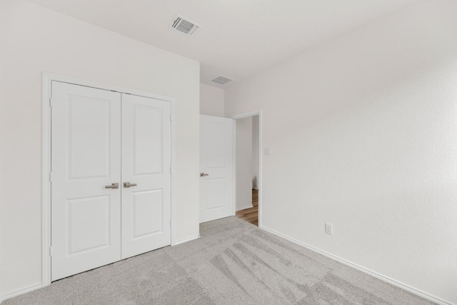 unfurnished bedroom with a closet, baseboards, carpet flooring, and visible vents