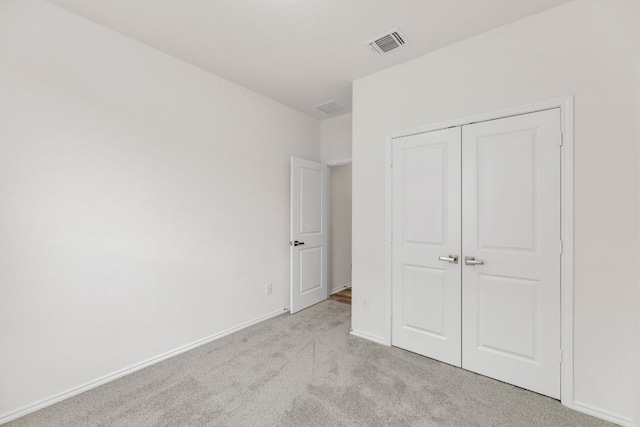 unfurnished bedroom featuring visible vents, carpet flooring, baseboards, and a closet
