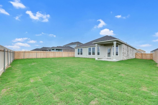 rear view of house with a fenced backyard, a patio area, and a yard