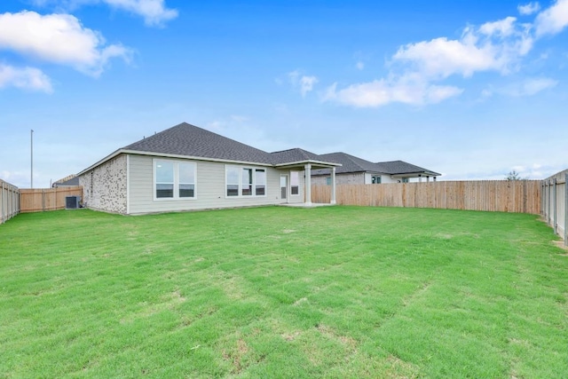 rear view of house with a fenced backyard, a yard, and cooling unit
