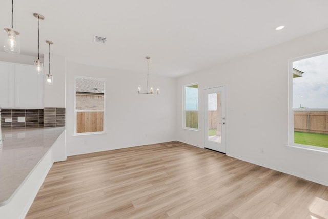 unfurnished dining area featuring recessed lighting, visible vents, an inviting chandelier, and light wood finished floors