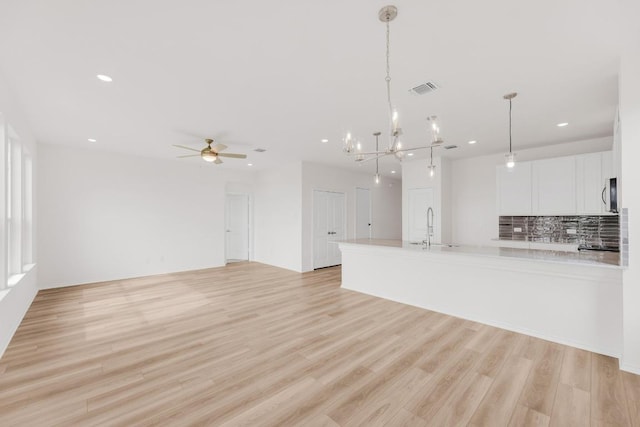 kitchen with recessed lighting, light countertops, white cabinetry, stainless steel microwave, and a sink