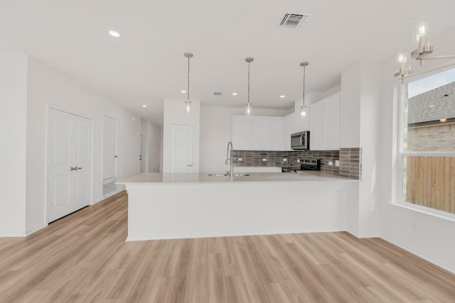 kitchen with appliances with stainless steel finishes, a sink, light countertops, light wood-type flooring, and visible vents
