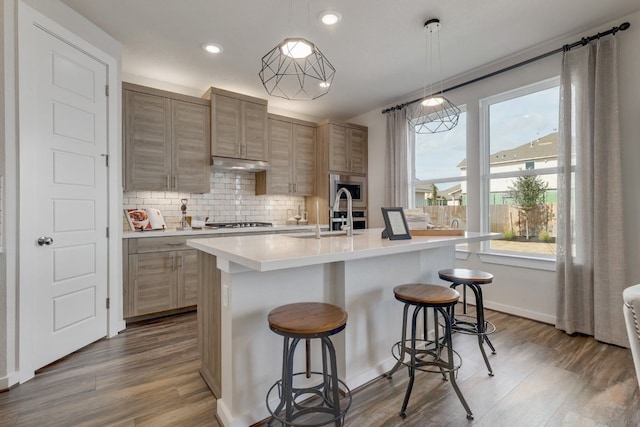 kitchen featuring a kitchen island with sink, sink, hanging light fixtures, and appliances with stainless steel finishes