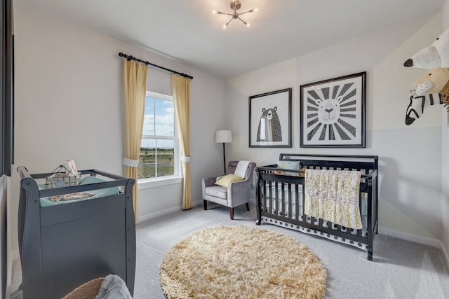 bedroom with a crib, light colored carpet, and an inviting chandelier