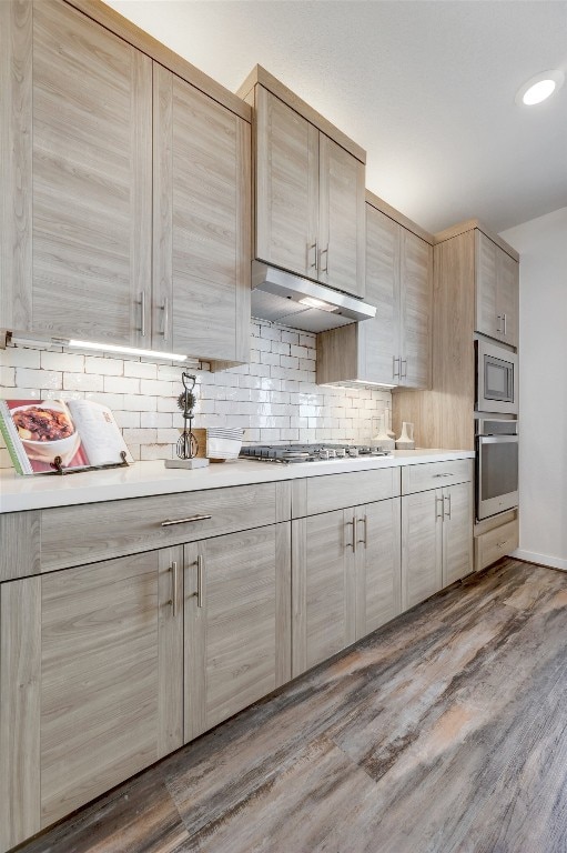 kitchen with decorative backsplash, light brown cabinets, stainless steel appliances, and wood-type flooring