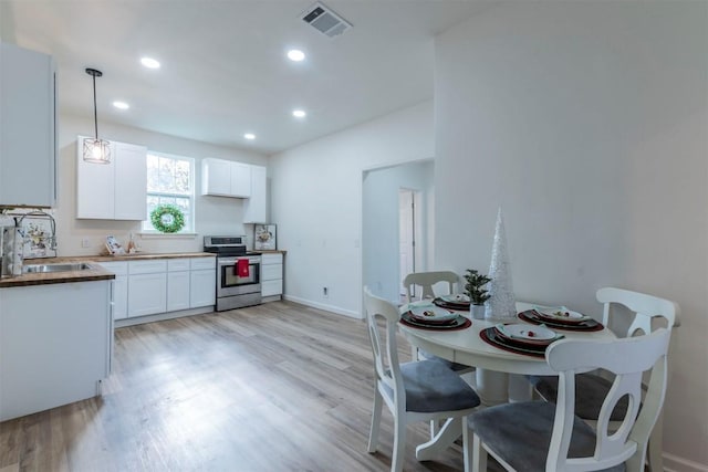 kitchen with white cabinets, stainless steel electric range oven, hanging light fixtures, and sink