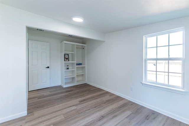 empty room with a healthy amount of sunlight and light hardwood / wood-style flooring