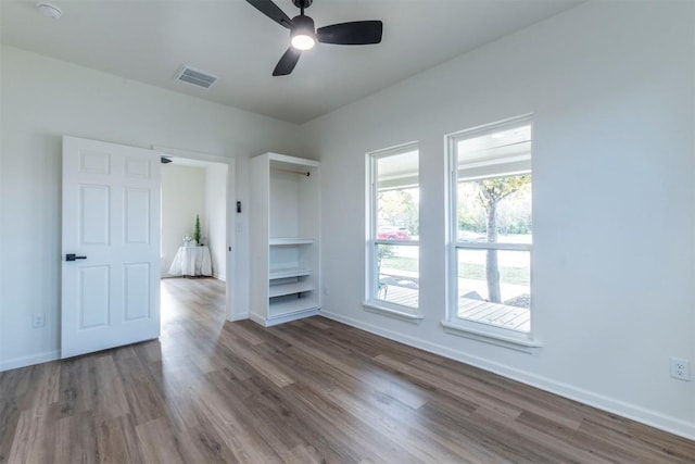 unfurnished room with ceiling fan, wood-type flooring, and built in features