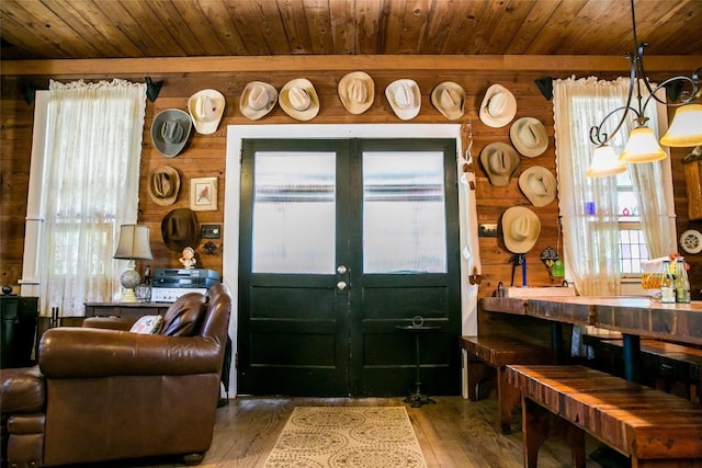 foyer featuring wood-type flooring, wooden walls, an inviting chandelier, and wooden ceiling