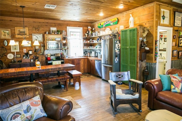 interior space with wood walls, light wood-type flooring, sink, and wood ceiling