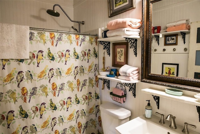 bathroom featuring toilet, wooden walls, sink, and a shower with shower curtain